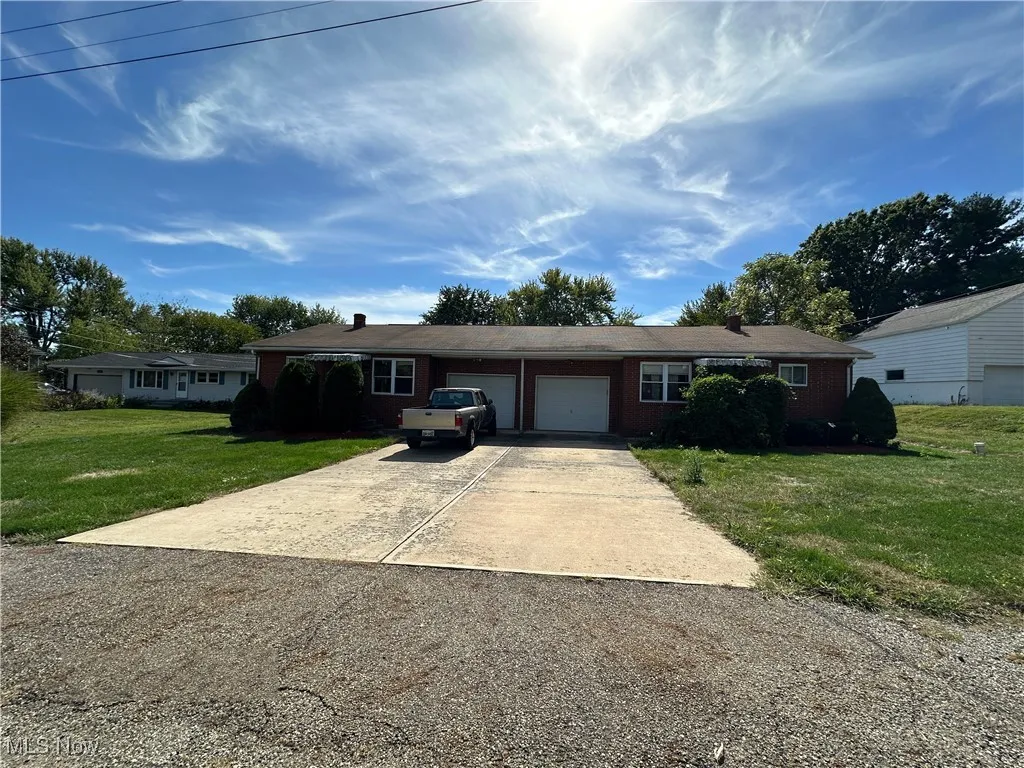 Ranch-style house with a front lawn, concrete driveway, brick siding, and an attached garage