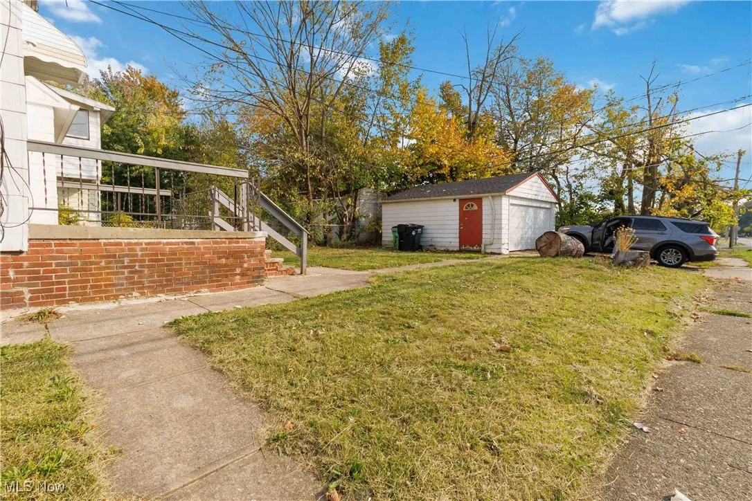 View of grassy yard featuring an outbuilding, a detached garage, and stairs