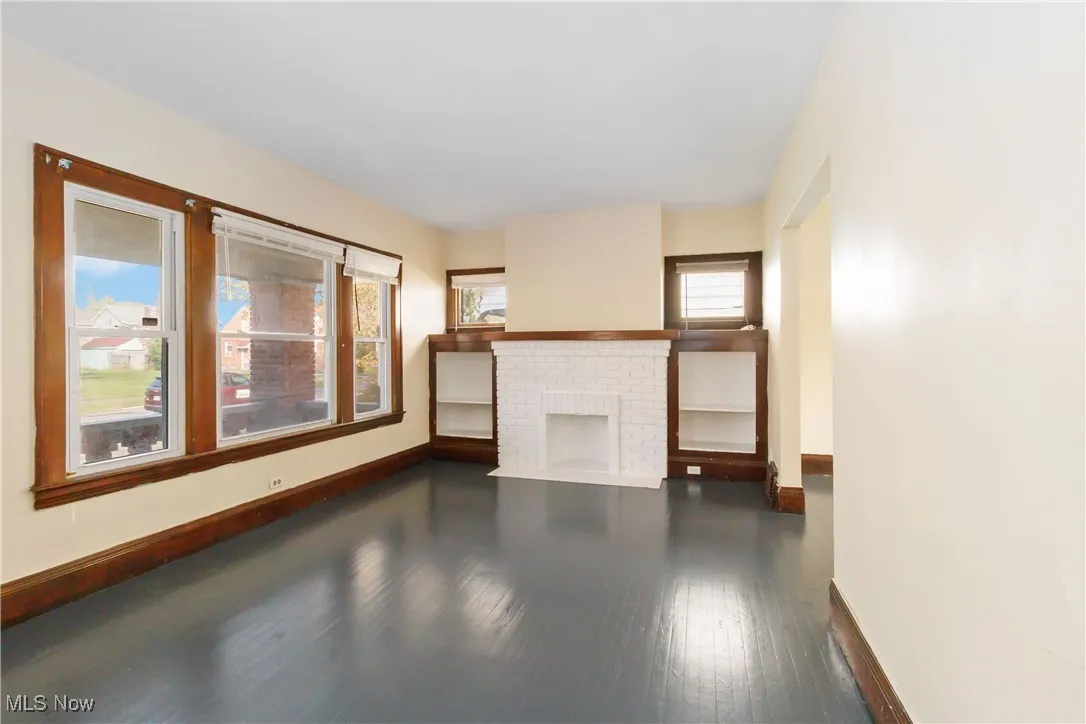 Unfurnished living room with dark wood-type flooring and a fireplace
