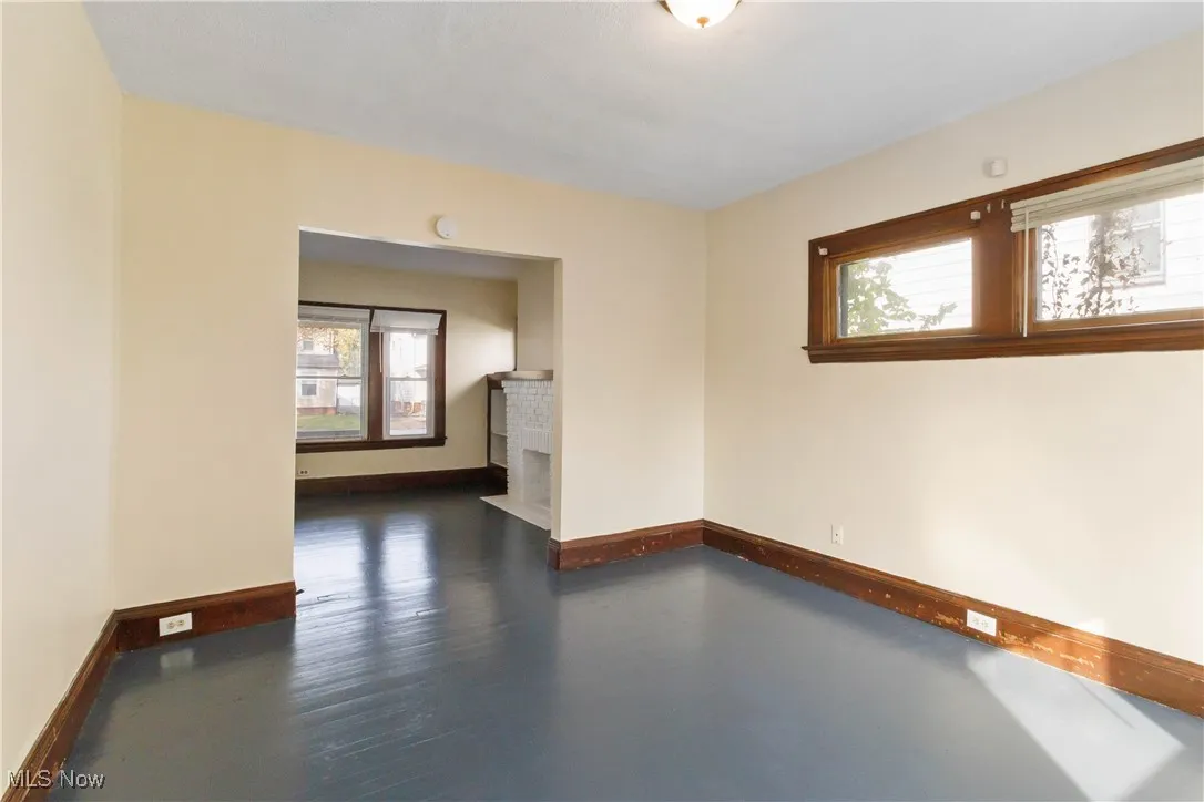 Empty room with dark wood finished floors and a fireplace