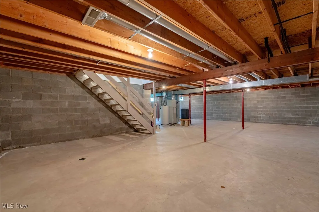 Unfinished basement with stairway and water heater