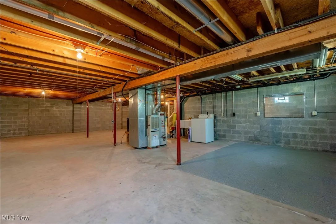 Unfinished below grade area with washer / clothes dryer, heating unit, and concrete block wall