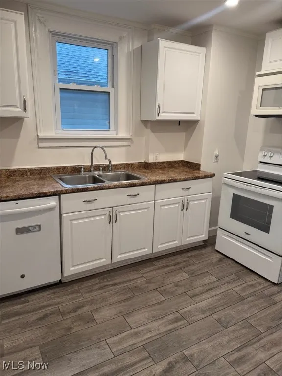 Kitchen featuring dark countertops, white appliances, white cabinetry, and dark wood-type flooring