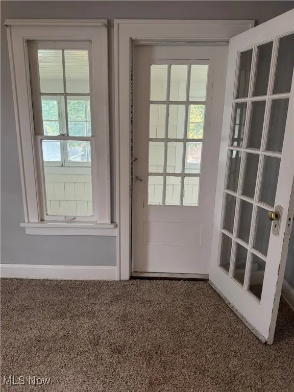 Doorway with baseboards and carpet flooring