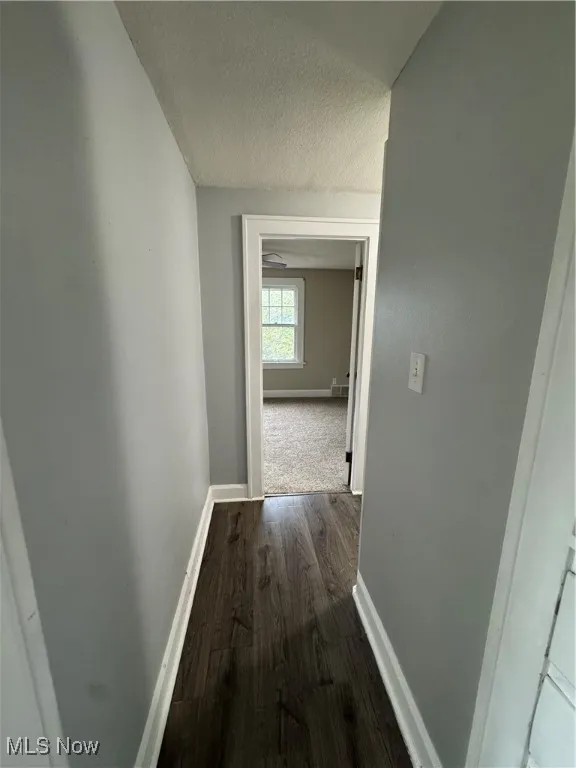 Hall with a textured ceiling and dark wood-style floors