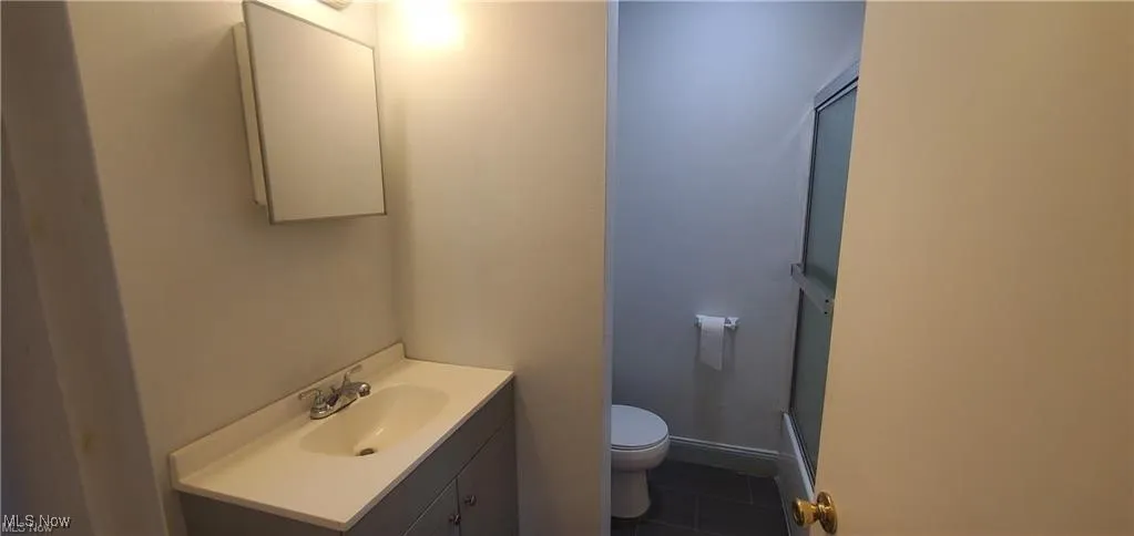 Full bath with vanity, dark tile patterned floors, and a shower stall