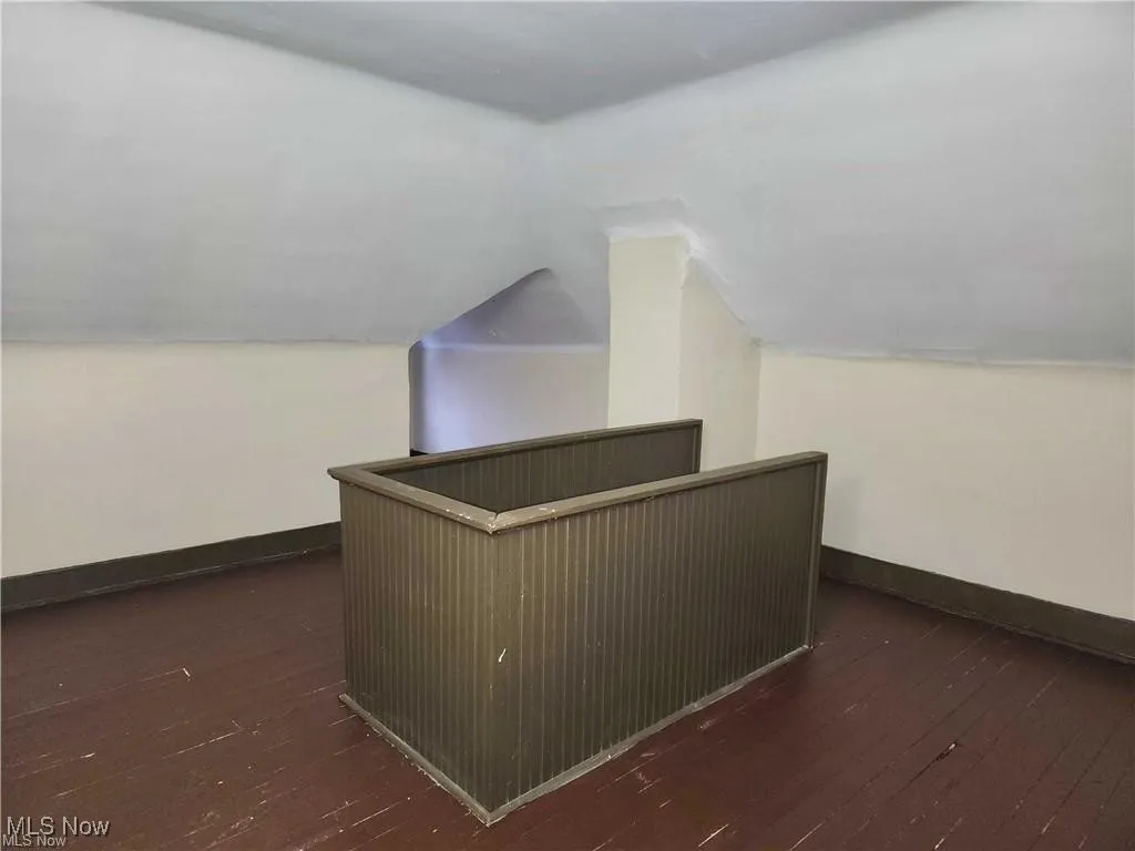 Additional living space with lofted ceiling and dark wood-type flooring