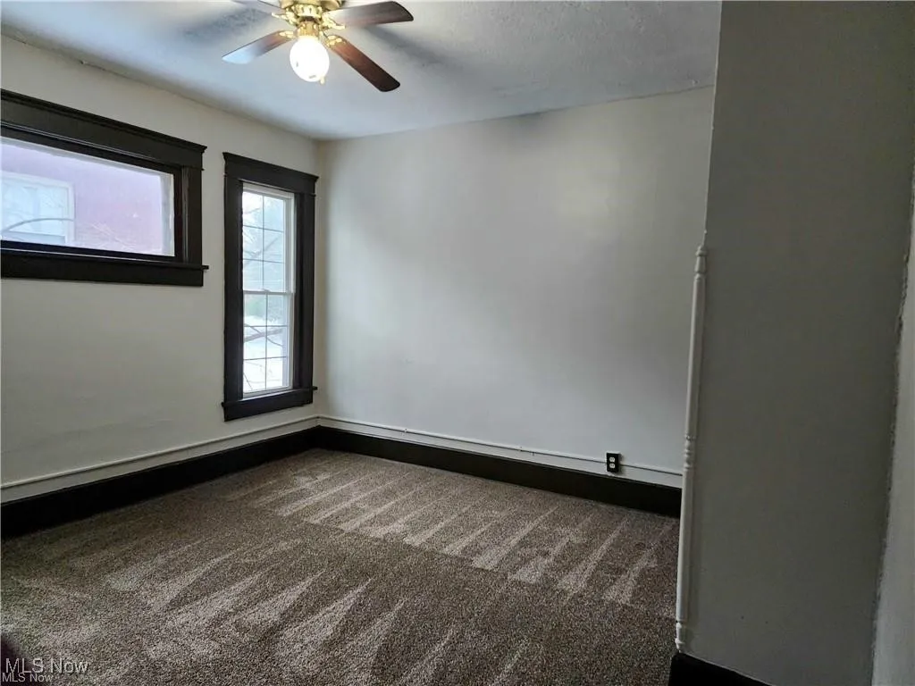 Spare room featuring dark colored carpet, ceiling fan, and a textured ceiling