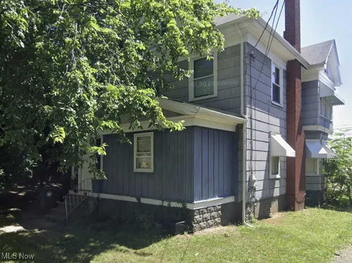View of side of home with a chimney and a yard
