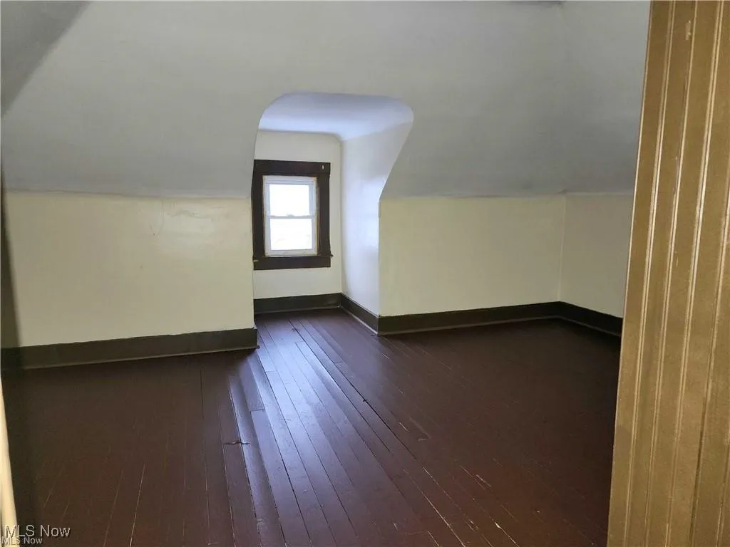 Additional living space with dark wood-style floors and lofted ceiling