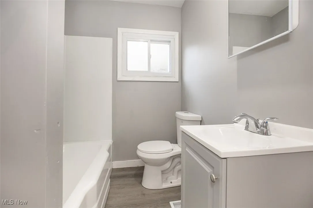Full bath with vanity, wood finished floors, and shower / tub combination