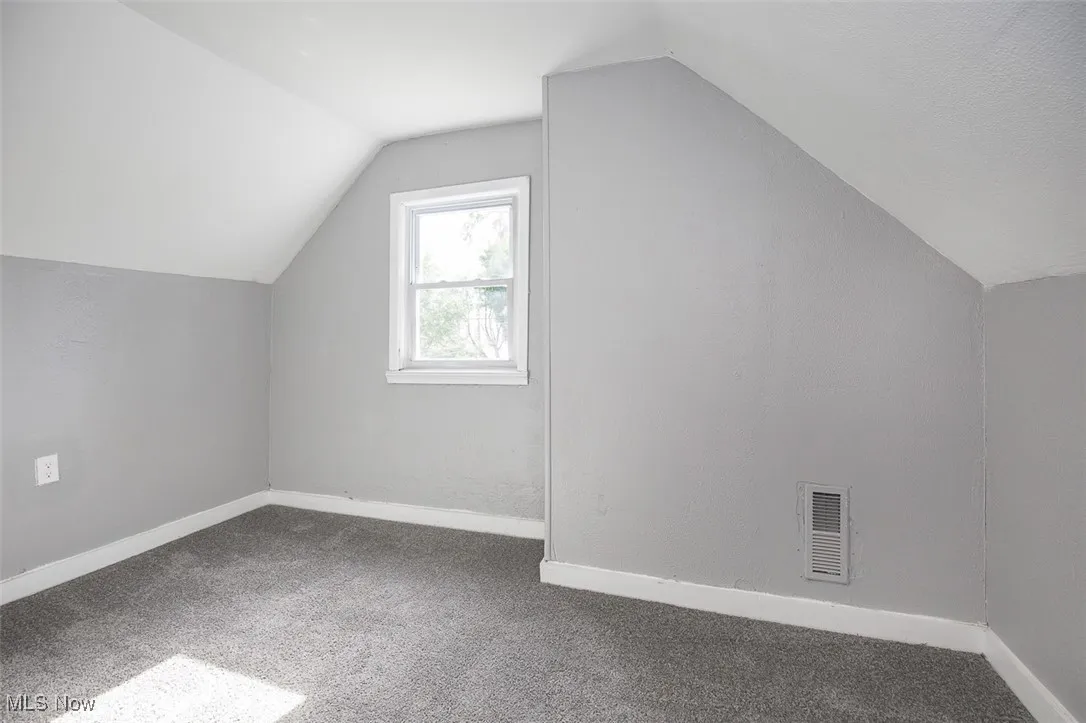 Additional living space with carpet floors and vaulted ceiling