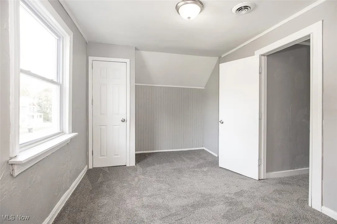 Additional living space with lofted ceiling and light colored carpet