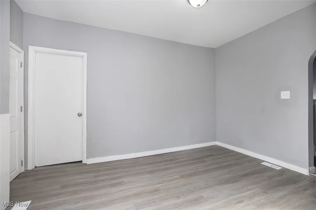 Empty room featuring arched walkways and light wood-style floors
