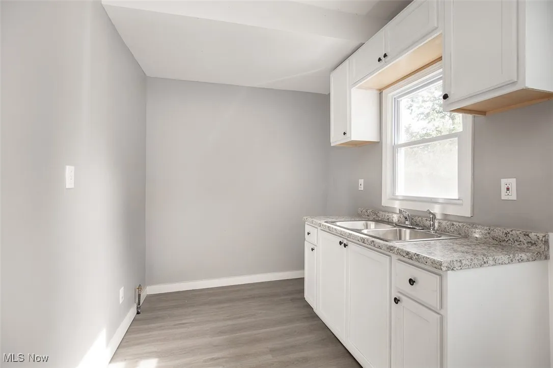 Kitchen with light countertops, light wood-type flooring, and white cabinets