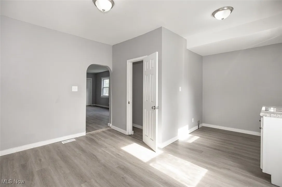 Spare room featuring arched walkways and light wood-style floors