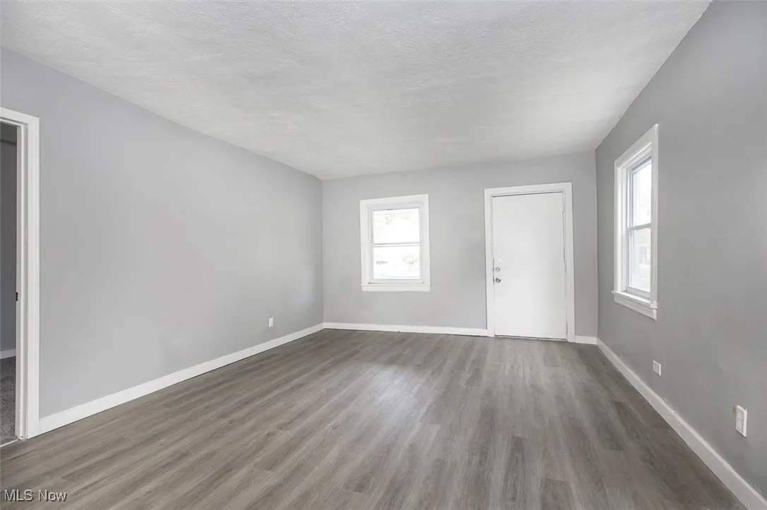 Unfurnished living room with dark wood-type flooring and a textured ceiling