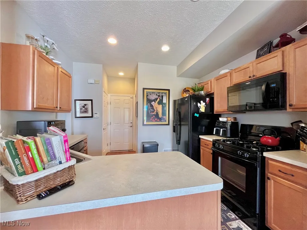 Kitchen featuring black appliances, light countertops, recessed lighting, and a peninsula