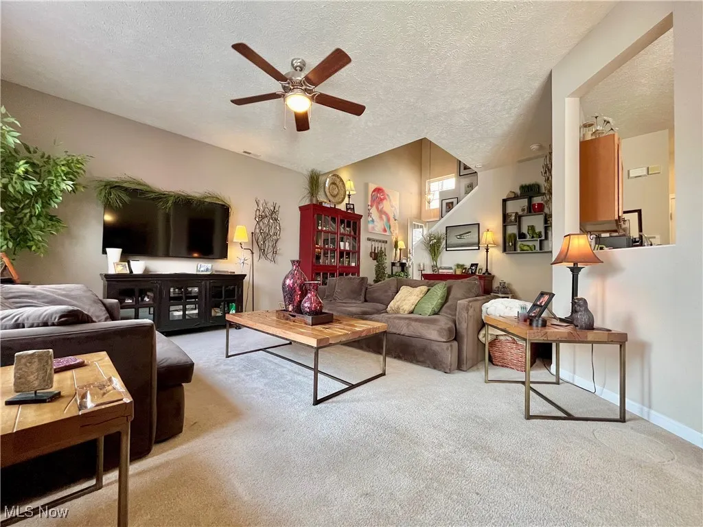 Carpeted living room featuring a ceiling fan