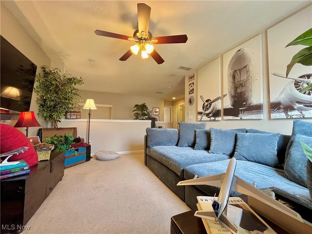 Carpeted loft area with ceiling fan