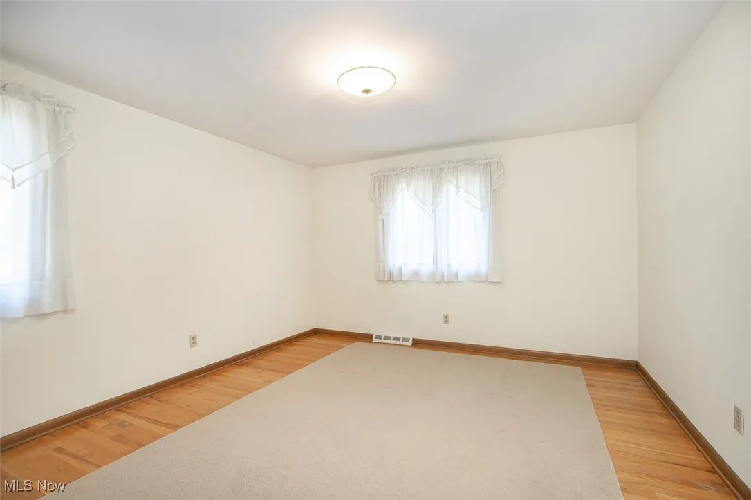 Spare room with baseboards and light wood-style flooring