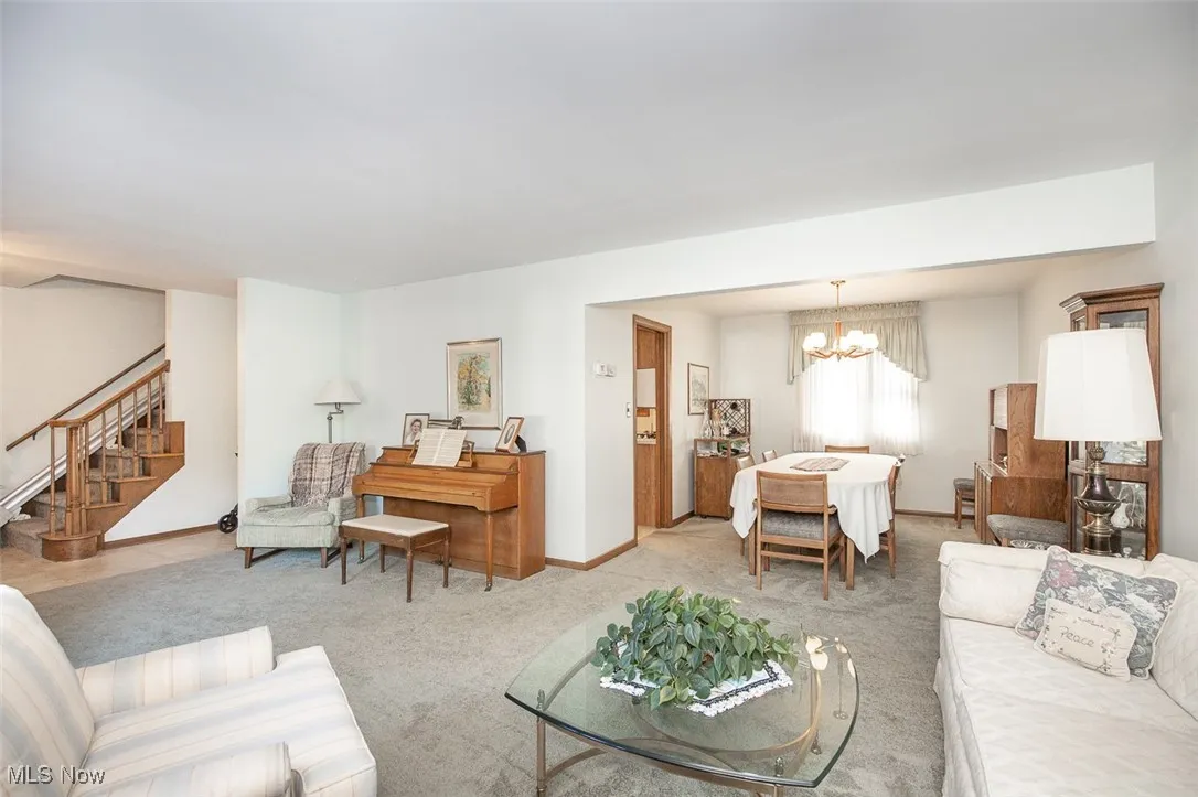 Carpeted living area featuring a chandelier and stairway