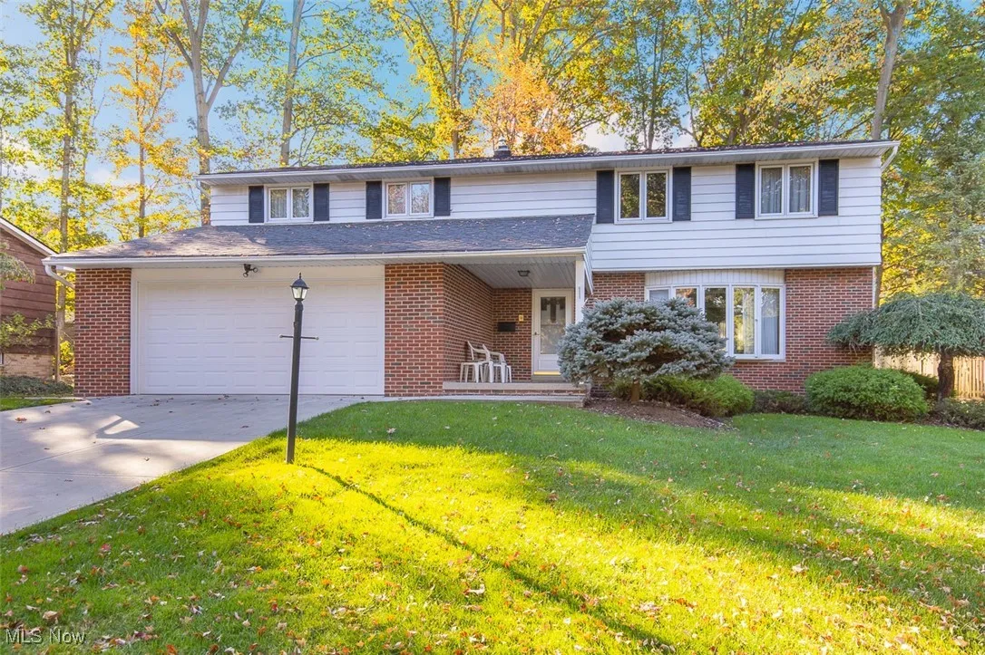 View of front of property with brick siding, driveway, a front yard, and an attached garage