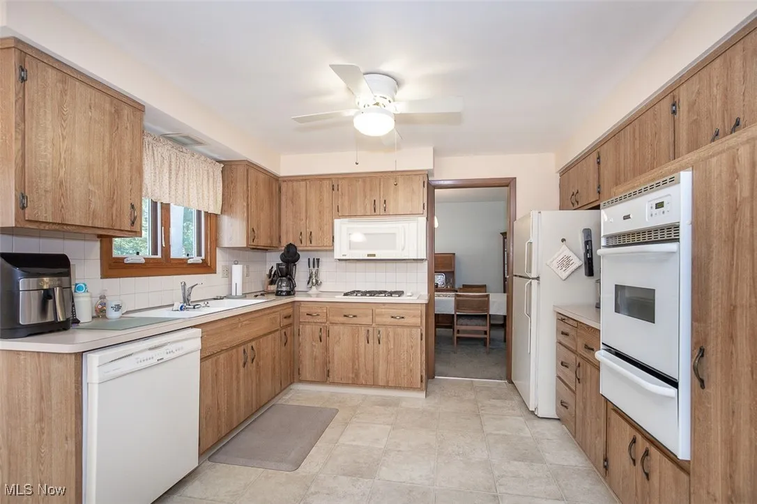Kitchen with white appliances, light countertops, decorative backsplash, and a warming drawer