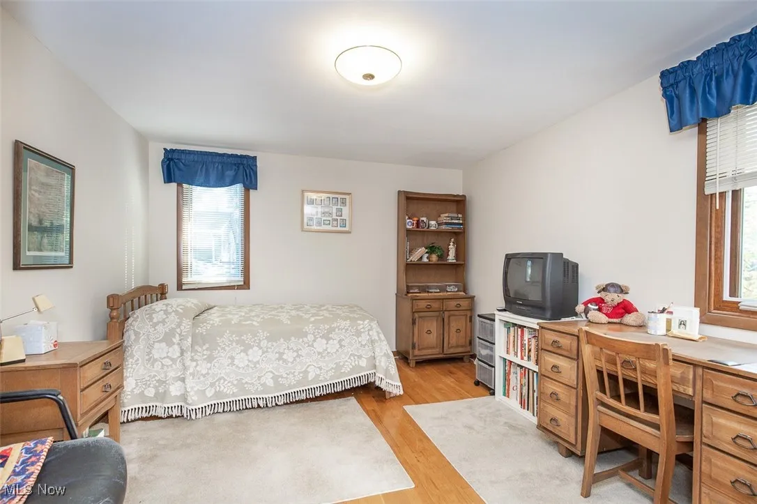 Bedroom with light wood-style flooring, multiple windows, and an office area
