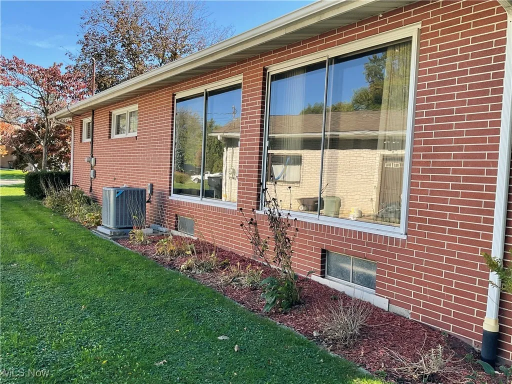 View of property exterior featuring a yard, brick siding, and cooling unit