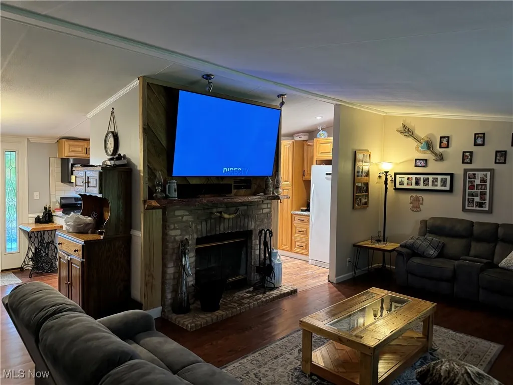 Living room with crown molding, wood finished floors, and a brick fireplace