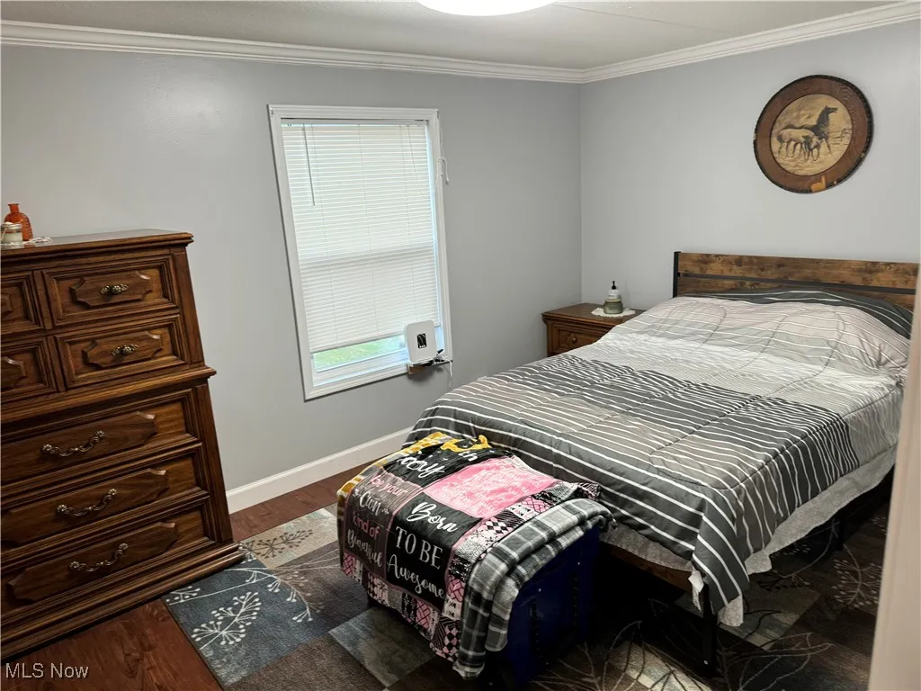 Bedroom featuring crown molding and dark wood-style flooring