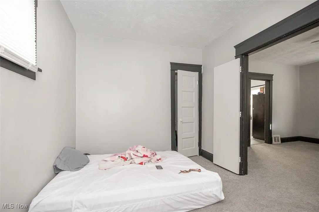 Bedroom featuring a textured ceiling and light colored carpet