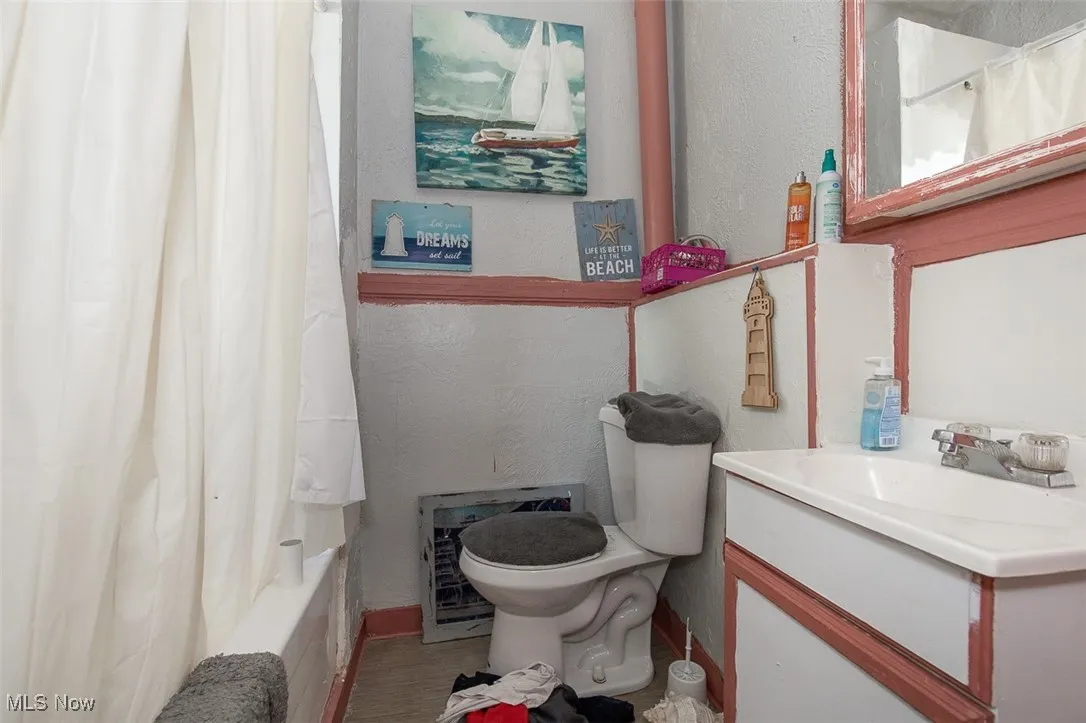 Full bath featuring a textured wall, vanity, and shower / bathtub combination with curtain