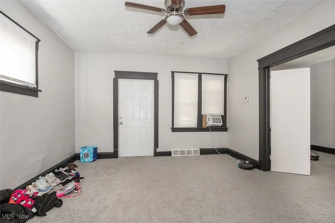 Empty room with carpet floors, plenty of natural light, a ceiling fan, and a textured ceiling