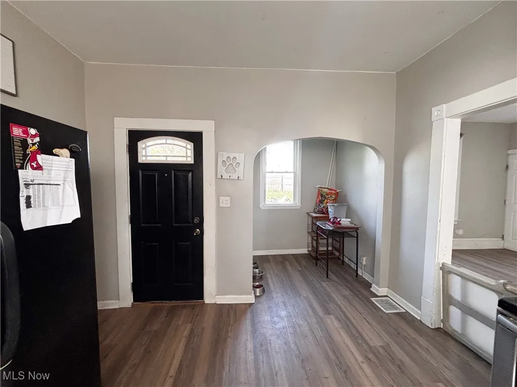 Foyer with dark wood-style floors and arched walkways