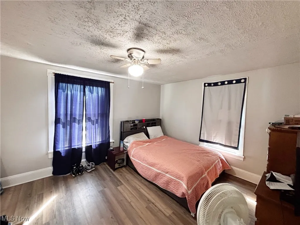 Bedroom featuring wood finished floors, a textured ceiling, and a ceiling fan