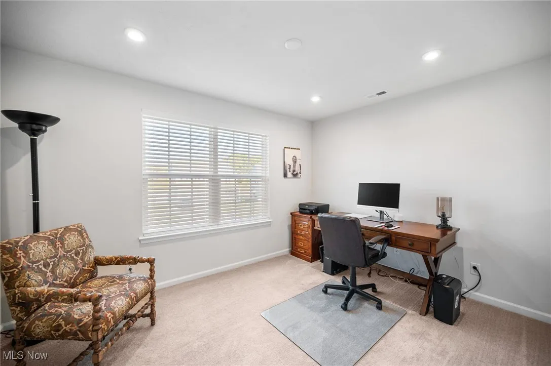 Office with light carpet and recessed lighting