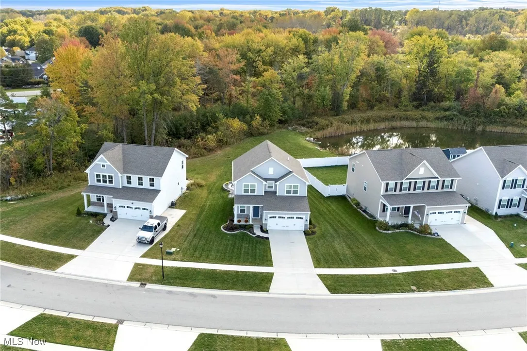 Aerial perspective of suburban area with a large body of water and a forest
