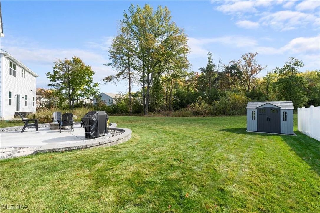 View of grassy yard featuring a patio area and a shed