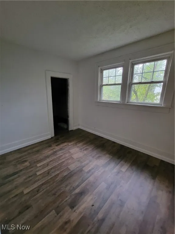 Spare room featuring dark wood-style floors and a textured ceiling