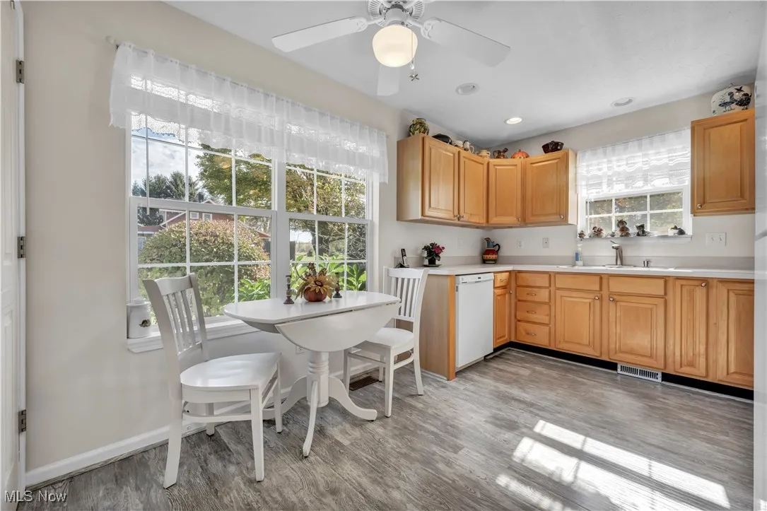 Kitchen featuring light countertops, light wood finished floors, white dishwasher, light brown cabinetry, and recessed lighting