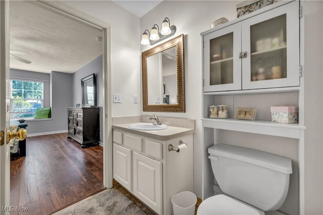 Bathroom featuring vanity, dark wood-style floors, ceiling fan, and a textured ceiling
