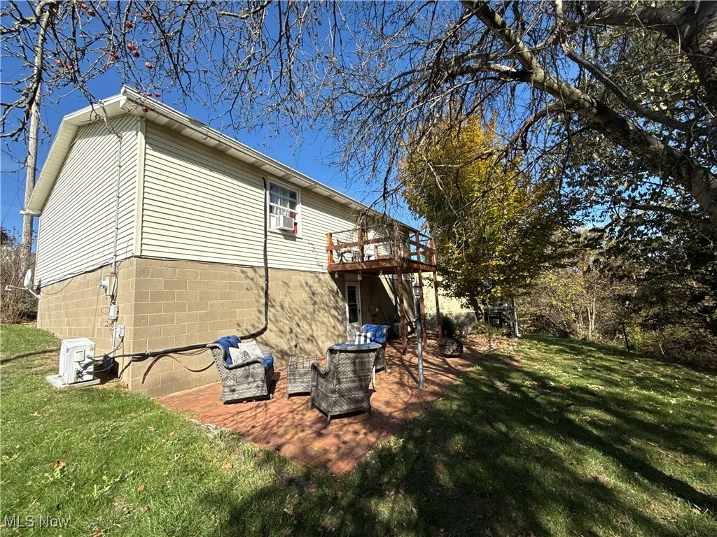 View of property exterior with a lawn, a deck, and a patio area