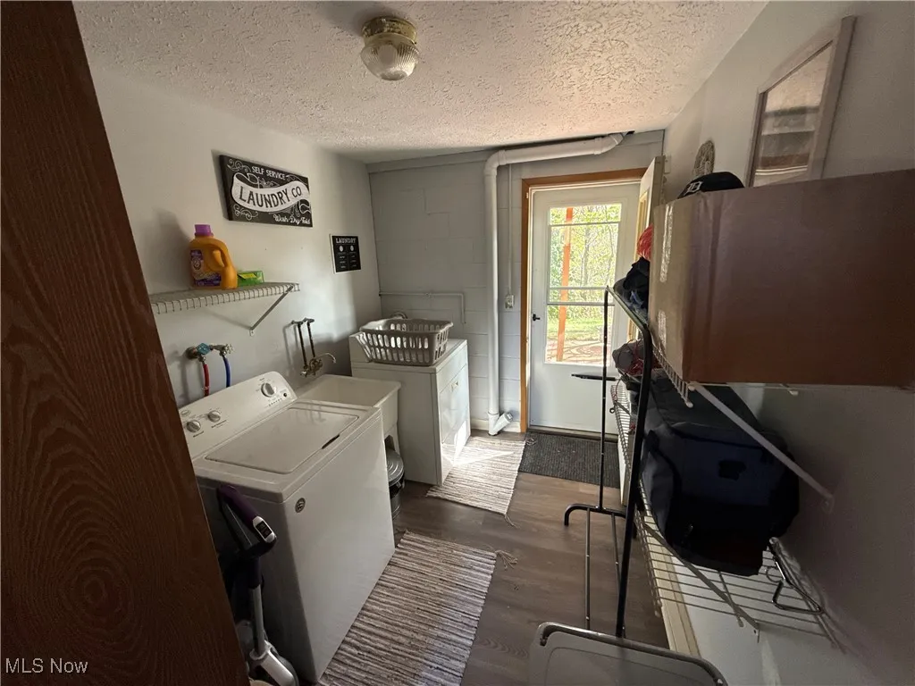 Laundry room with dark wood finished floors, a textured ceiling, and washing machine and dryer