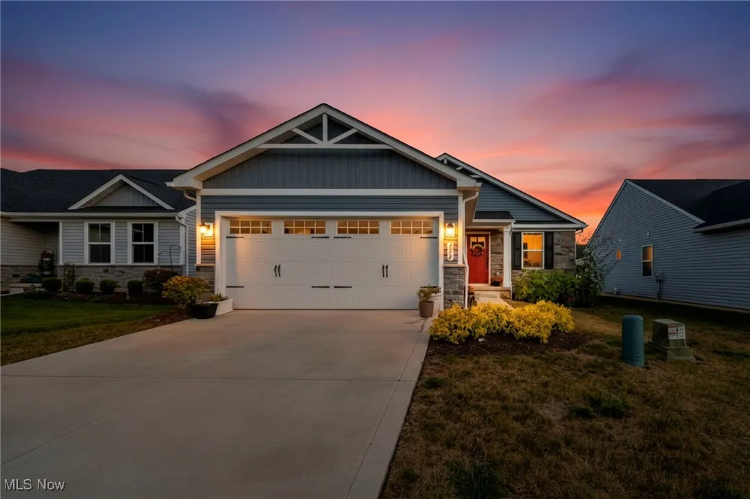 Craftsman-style house featuring stone siding, an attached garage, and board and batten siding