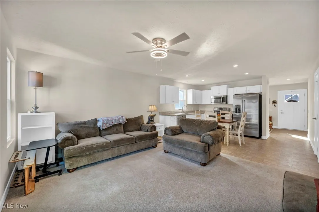 Living room with a ceiling fan, light colored carpet, and recessed lighting