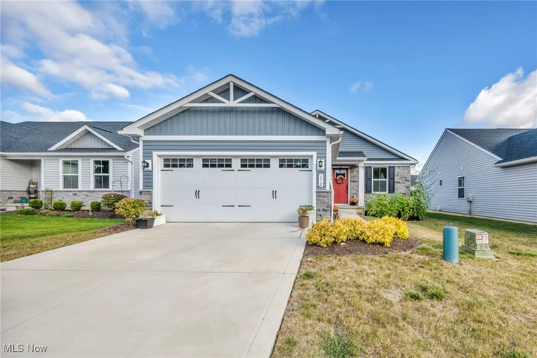 Craftsman-style house featuring stone siding, board and batten siding, a front yard, and a garage