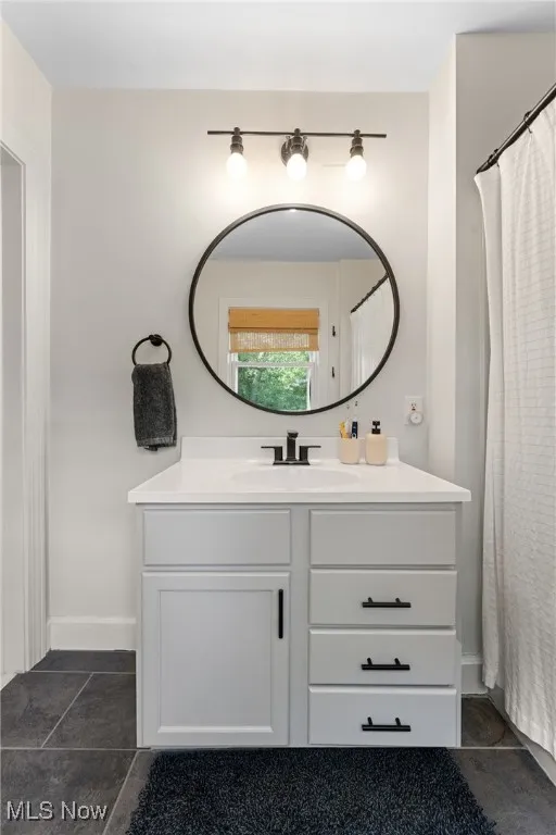 Full bath featuring curtained shower, vanity, and dark tile patterned floors