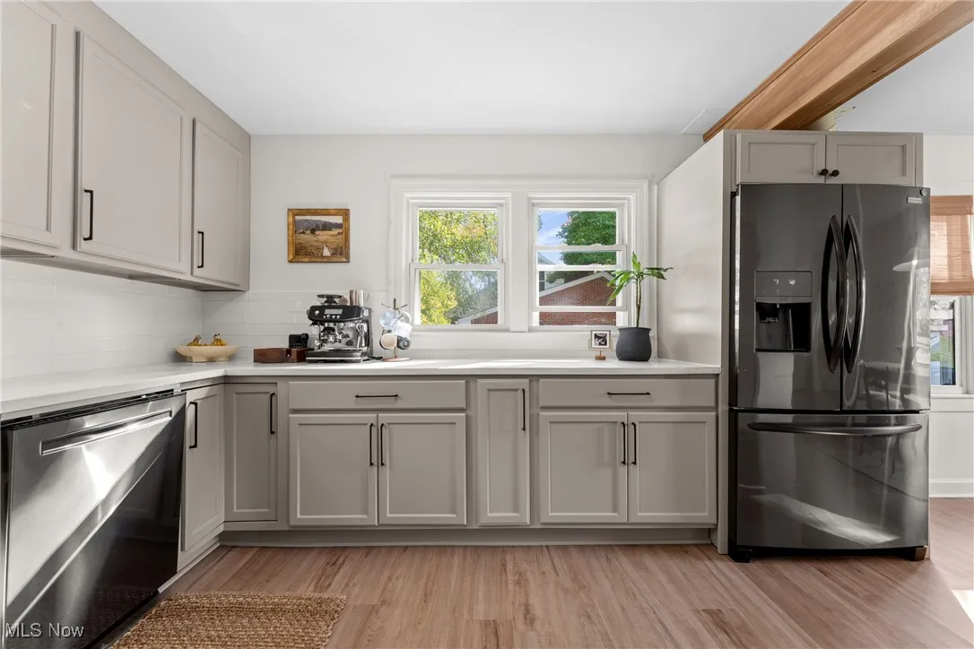 Kitchen featuring appliances with stainless steel finishes, gray cabinets, light wood-style floors, and decorative backsplash